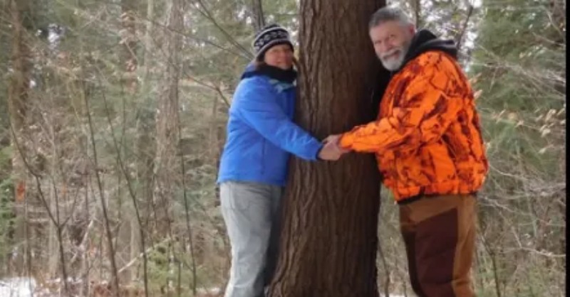 A man and woman holding hands next to a tree.